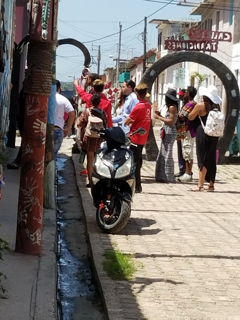 A study-abroad group gathered along a narrow Cuban street framed by painted archways and a parked motorbike